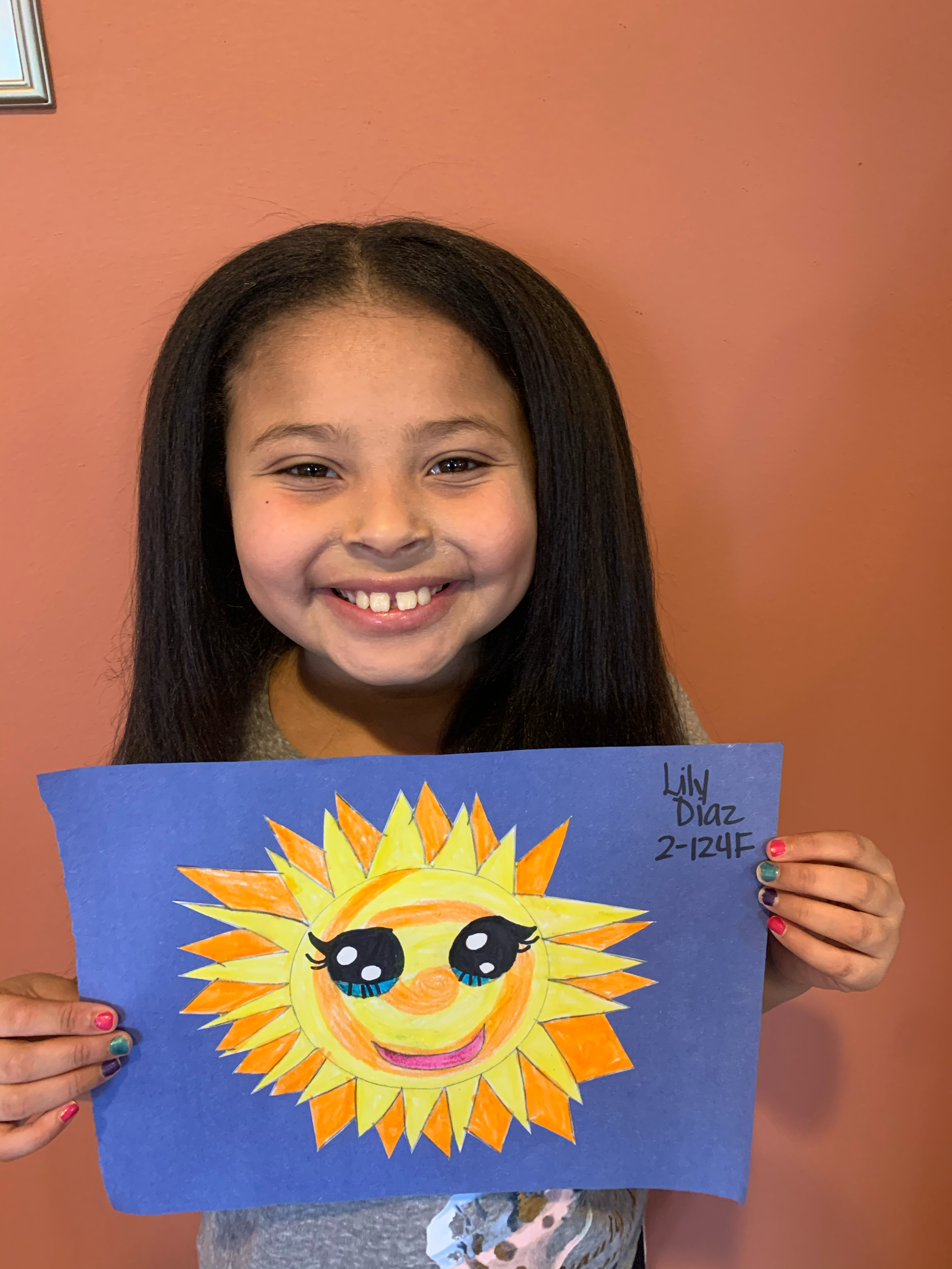 Young girl proudly holding up her drawing of a sun