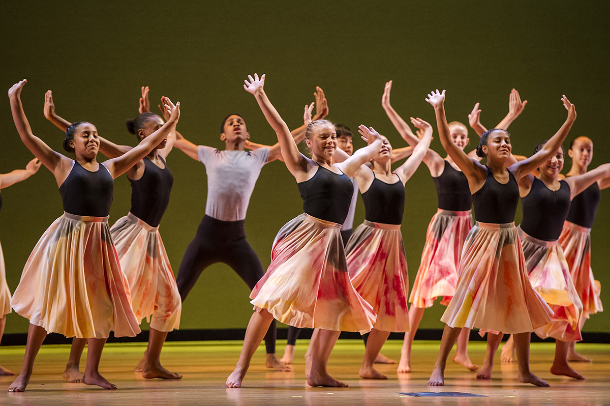 A photo of student dancers posing with their hands extended upwards at SAI Finale 