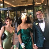 Three students standing outside the entrance to a hotel ballroom with formal attire on.