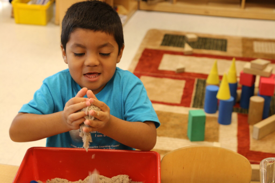 A child plays with sand at sand box area for center time. 