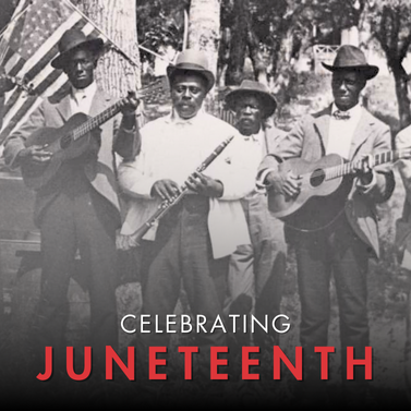 Six men, the Emancipation Day Band, in the year 1900. They are carry instruments, wearing suits and hats, and in front of an American flag.