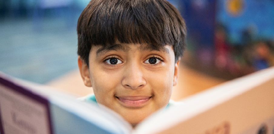 Image of a smiling boy behind a book