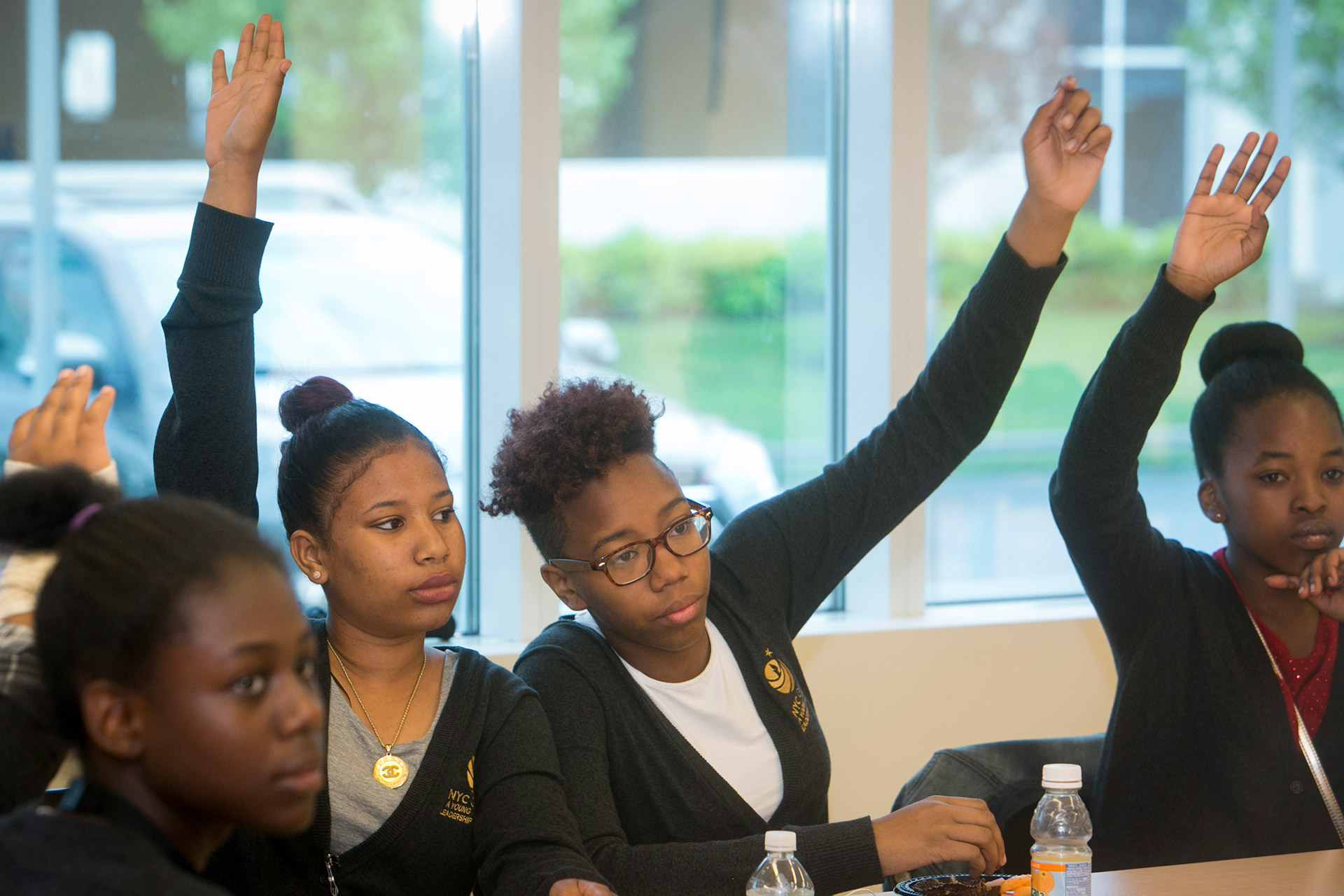 Two girls in class raising their hands