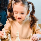 Close-up of young girl moving chess pieces on a chessboard