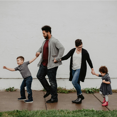 Two adults walking with two children walking hand-in-hand and walking in a line.