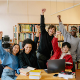 Five students with raised arms in celebration at a library