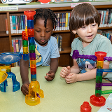 Two children in a library playing with a toy.