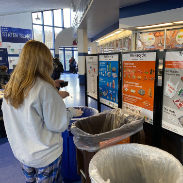 A student in a school cafeteria sorting their recyclables.