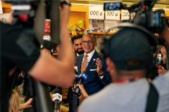 Chancellor David Banks surrounded by a gaggle of reporters while standing inside a school library