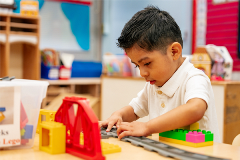 A young pre-schooler playing with LEGO bricks after settling in on his first day of school.