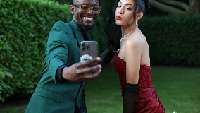 A young man and woman dressed in formal attire and taking a selfie.