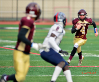 Action photo of Grady HS QB, Leonid Borock (#4), running with a football with defenders from Jamaica H.S. ready to stop him.