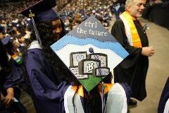Close-up of the top of a graduation cap; the cap features an assortment of viewing monitors with "2024" and a capital "B" on two of the screens. The cap reads, "Ctrl the future"
