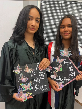 Two young ladies standing with graduation caps that read, "Time for the next adventure"