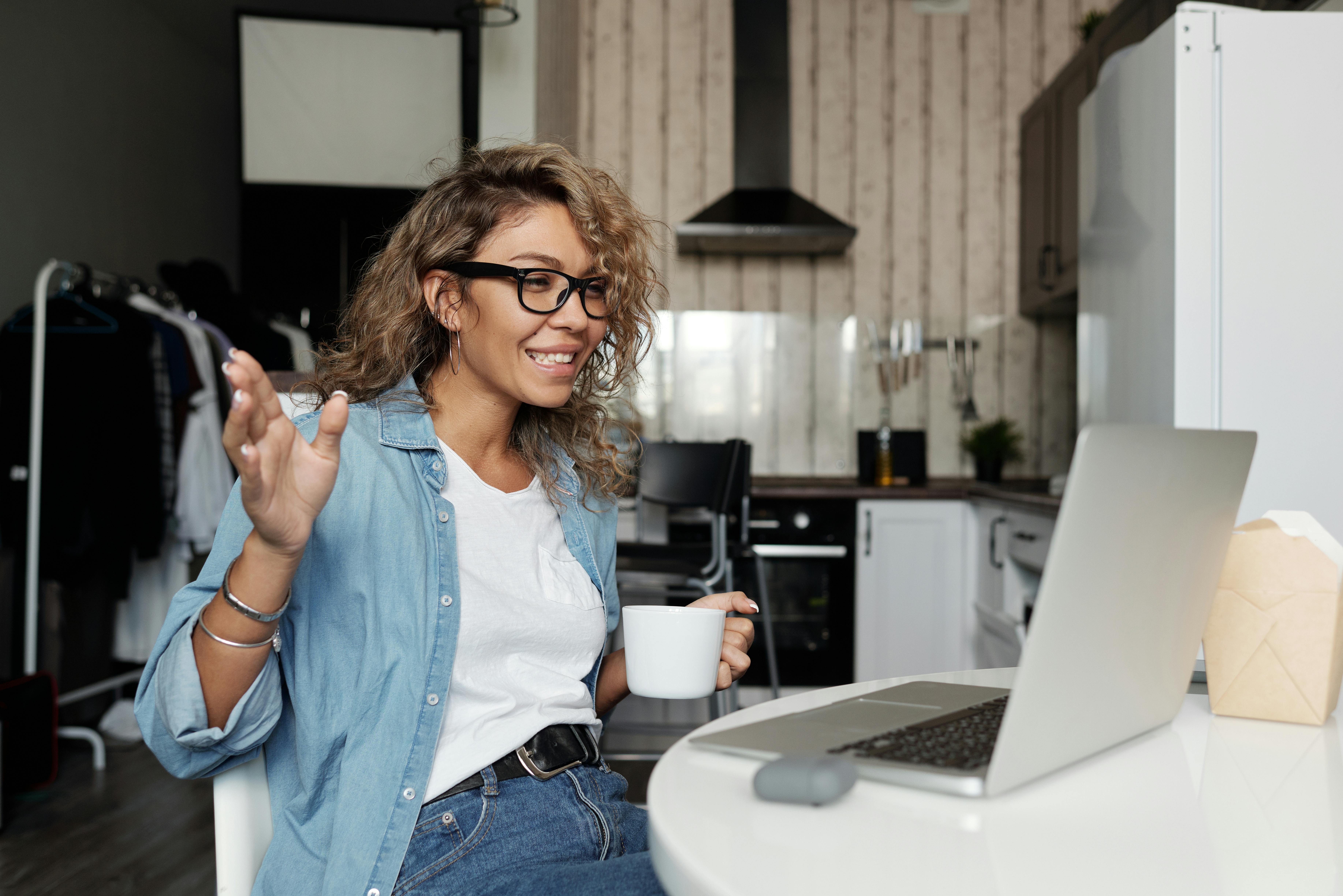 A woman drinking from a cup on video call